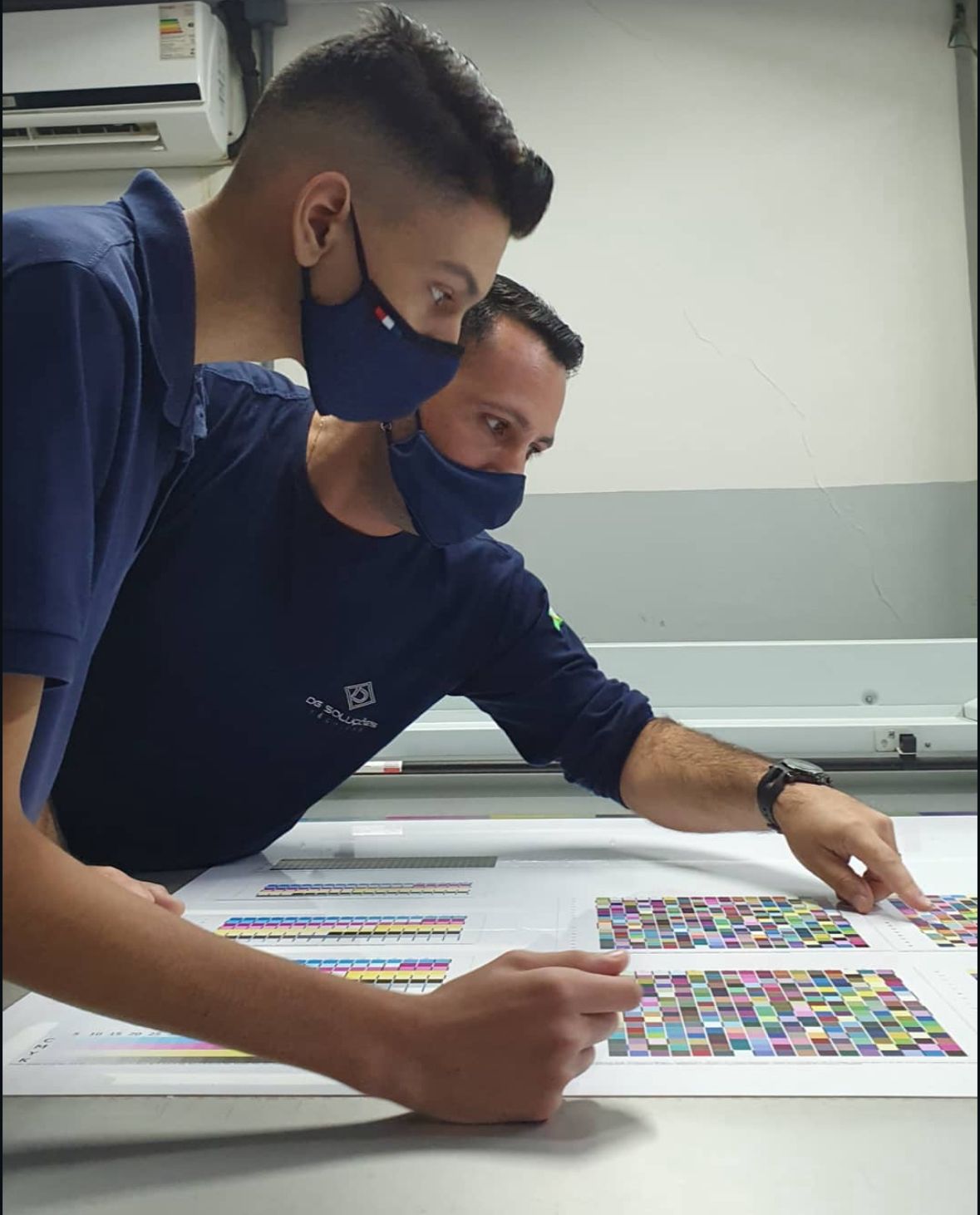 Técnicos conferindo padrões de cor em impressão de grande formato